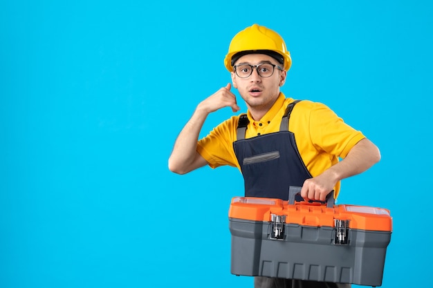 Vista frontal apresurando trabajador masculino en uniforme amarillo con caja de herramientas azul