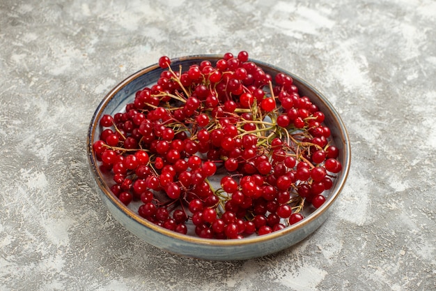 Vista frontal de arándanos rojos frescos dentro de la bandeja en la mesa blanca color baya fruta roja salvaje