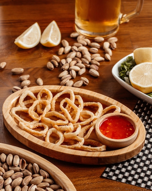 Una vista frontal de aros de cebolla con salsa de cacahuetes de cerveza en la mesa de madera marrón comida snack