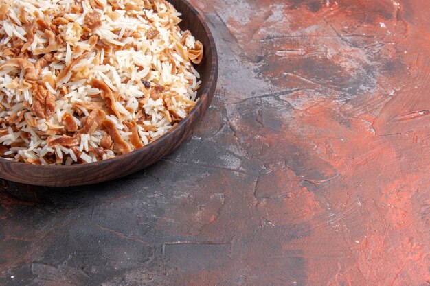 Vista frontal de arroz cocido con rebanadas de masa en la superficie oscura foto plato comida comida oscura
