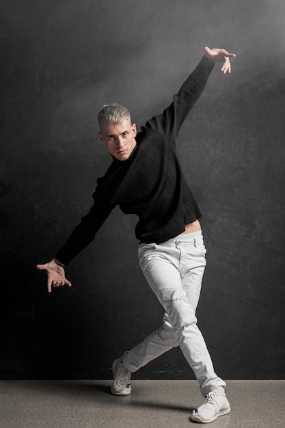 Vista frontal del artista masculino en jeans y zapatillas de deporte bailando