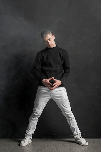Vista frontal del artista masculino posando en jeans y zapatillas de deporte