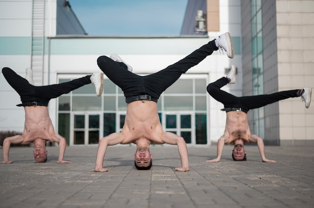 Vista frontal de artistas de hip hop sin camisa bailando sobre sus cabezas