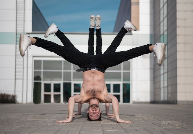 Vista frontal de artistas de hip hop sin camisa posando mientras baila