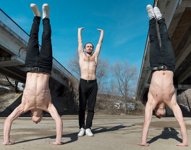 Vista frontal de artistas de hip hop sin camisa posando mientras practican danza