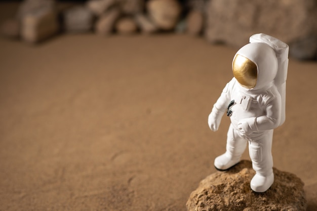 Vista frontal del astronauta blanco alrededor de piedras sobre negro