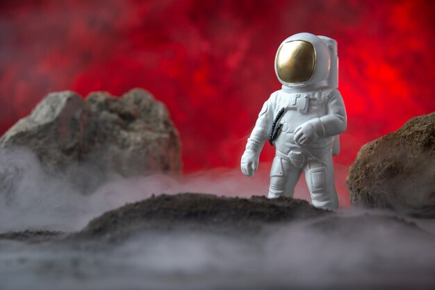 Vista frontal del astronauta blanco con rocas en la luna roja fantasía ciencia ficción cósmica