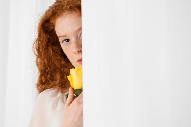 Vista frontal de la atractiva mujer posando con una flor de primavera y copie el espacio