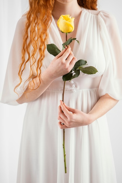 Vista frontal de la atractiva mujer posando con una flor de primavera