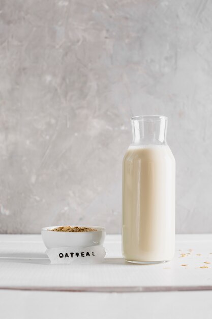 Vista frontal de avena con botella de leche en la mesa