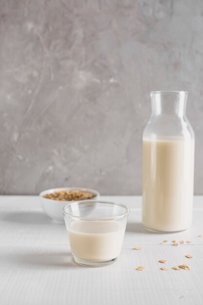 Vista frontal de avena con botella de leche y vidrio en la mesa