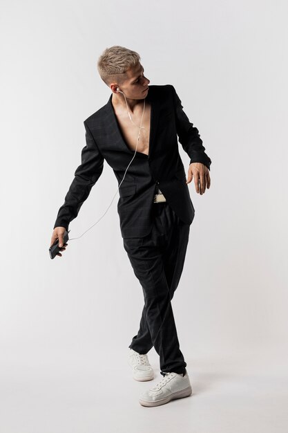 Vista frontal del bailarín en traje y zapatillas escuchando música con auriculares