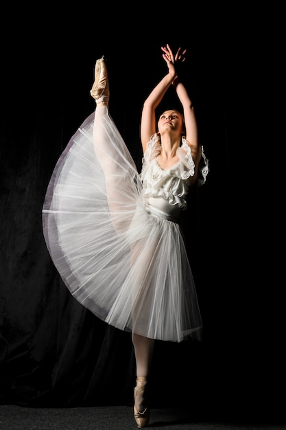 Vista frontal de la bailarina en vestido tutú con pierna arriba