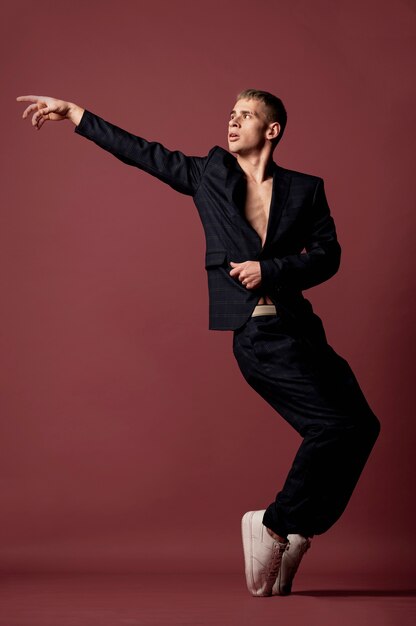 Vista frontal del baile masculino posando mientras muestra el movimiento de pie clásico del dedo del pie