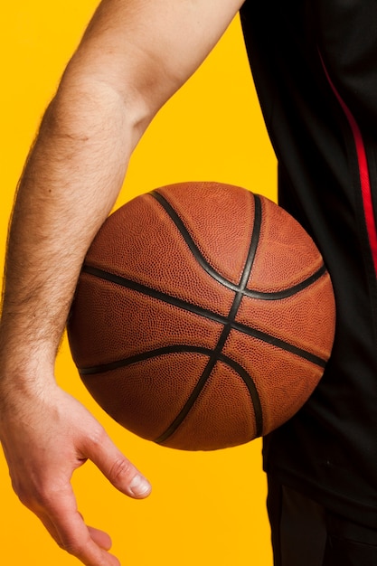 Vista frontal del baloncesto en manos del hombre cerca de la cadera