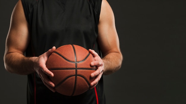 Vista frontal del baloncesto en manos del jugador masculino con espacio de copia