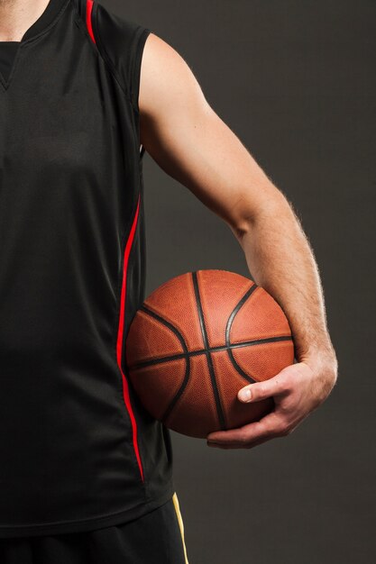 Vista frontal del baloncesto sostenido por el jugador cerca del cuerpo