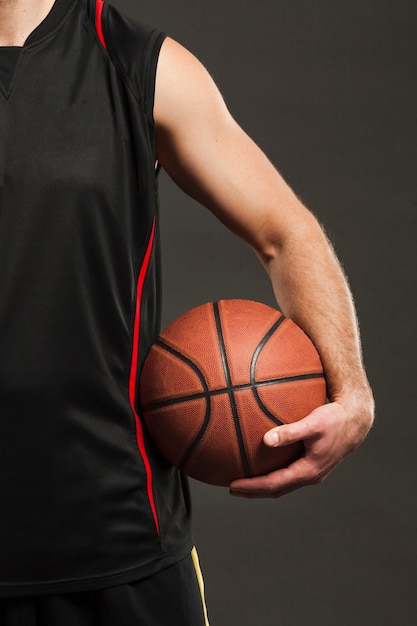 Vista frontal del baloncesto sostenido por el jugador cerca del cuerpo