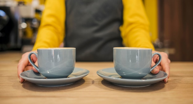 Foto gratuita vista frontal del barista con dos tazas de café.