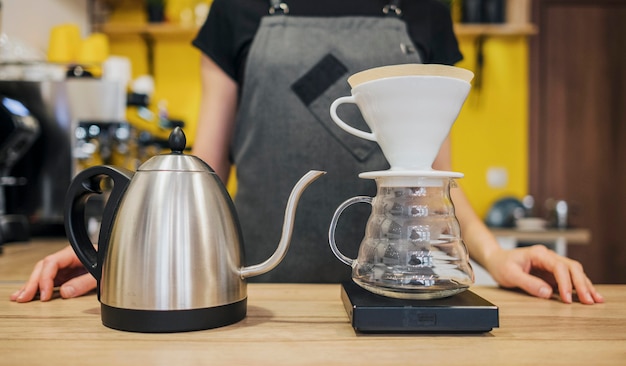 Vista frontal de barista con filtro de café y hervidor de agua