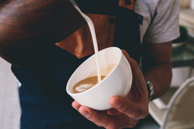 Vista frontal barista vierte leche en una taza de café