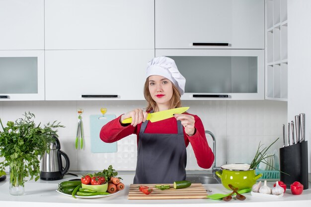 Vista frontal bastante cocinera en delantal sosteniendo un cuchillo