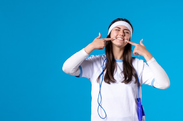 Vista frontal bastante mujer en ropa deportiva con saltar la cuerda en azul