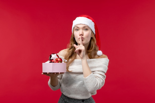 Foto gratuita vista frontal de bastante mujer sosteniendo juguetes de navidad en rojo