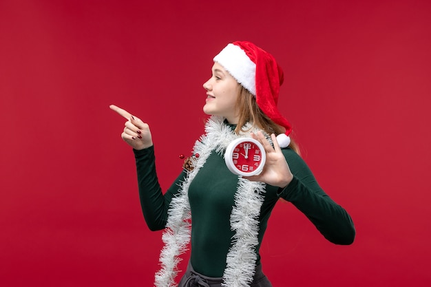 Foto gratuita vista frontal bastante mujer sosteniendo el reloj en el escritorio rojo