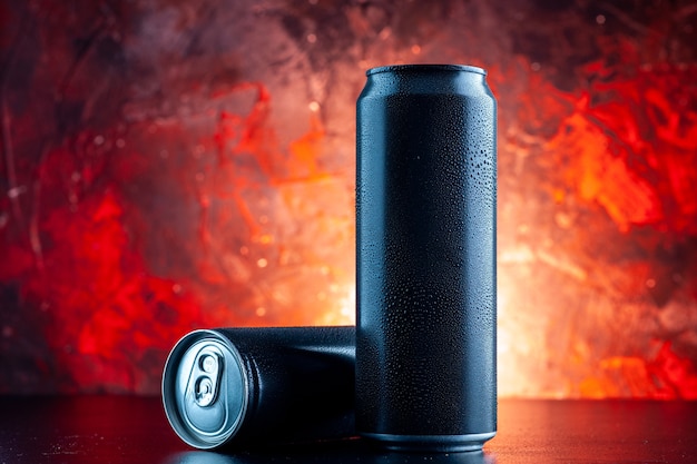 Vista frontal de la bebida energética en latas en la oscuridad de la foto de alcohol de bebida roja