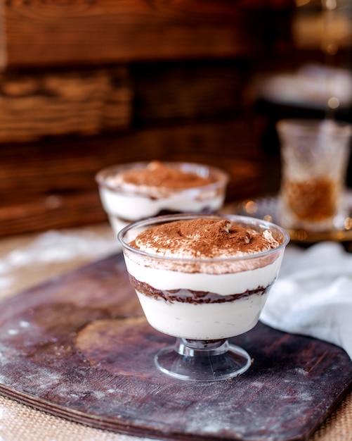 Vista frontal blanco delicioso postre dentro de pequeños vasos en el escritorio marrón