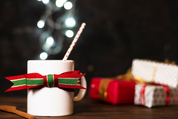 Vista frontal blanco taza de té con luces de navidad en el fondo