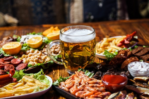 Foto gratuita vista frontal de bocadillos de cerveza con rodajas de limón en un soporte con un vaso de cerveza