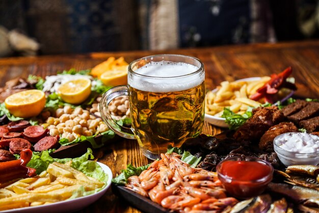 Vista frontal de bocadillos de cerveza con rodajas de limón en un soporte con un vaso de cerveza