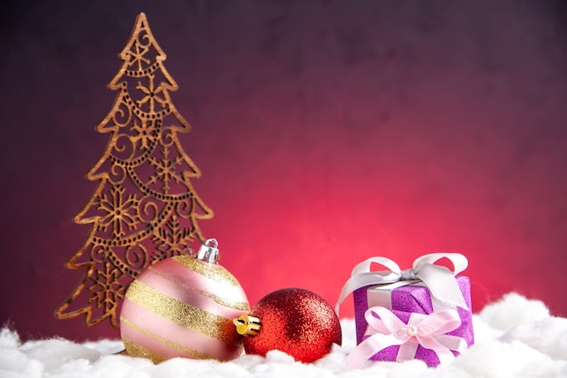 Foto gratuita vista frontal bolas de árbol de navidad decoración de navidad pequeños regalos sobre fondo rojo.