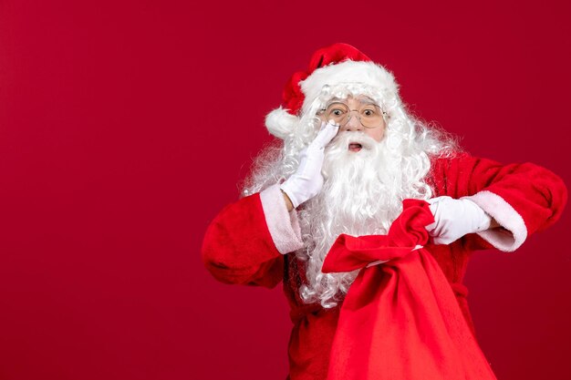 Vista frontal de la bolsa de apertura de santa claus llena de regalos para niños en las emociones navideñas de vacaciones rojas