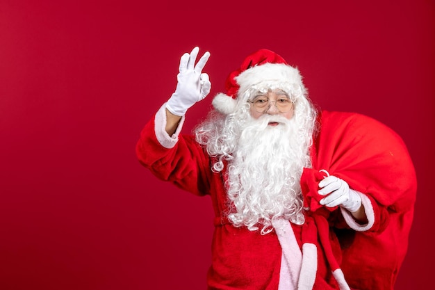 Vista frontal de la bolsa de transporte de santa claus llena de regalos en rojo emoción año nuevo navidad