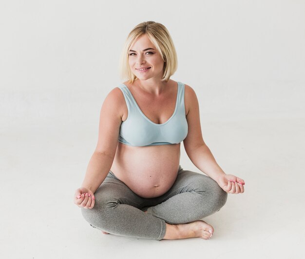 Vista frontal bonita mujer embarazada meditando
