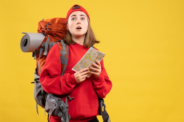 Vista frontal bonita mujer excursionista con mochila roja sosteniendo mapa mirando hacia arriba
