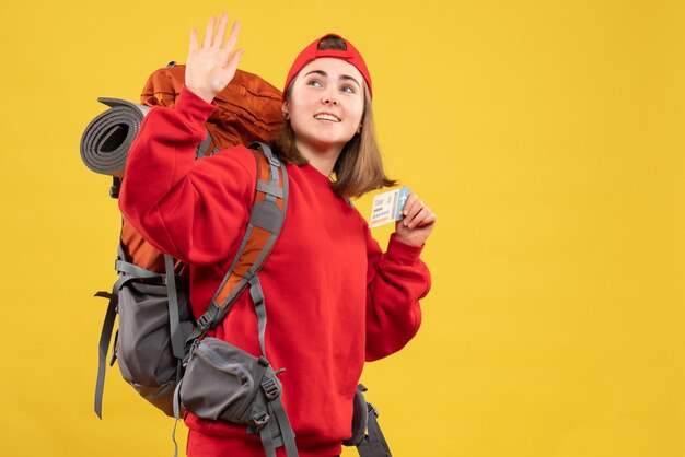 Vista frontal bonita mujer excursionista con mochila sosteniendo boleto de avión agitando la mano