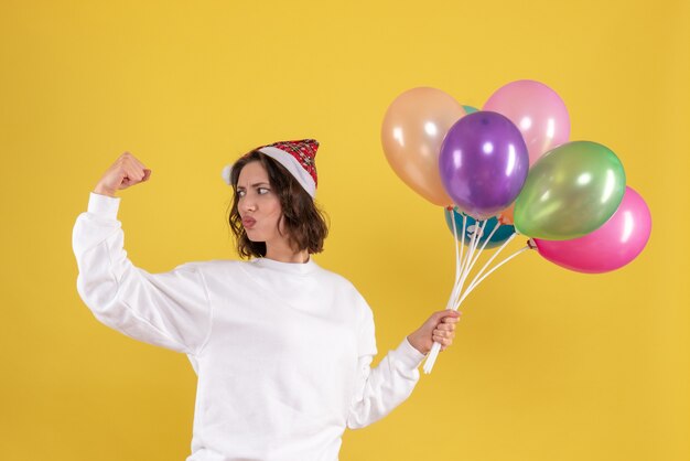 Vista frontal bonita mujer sosteniendo globos de colores en amarillo