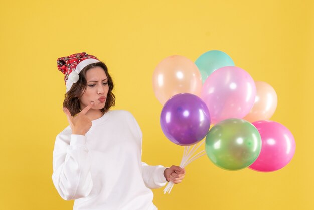 Vista frontal bonita mujer sosteniendo globos de colores en amarillo