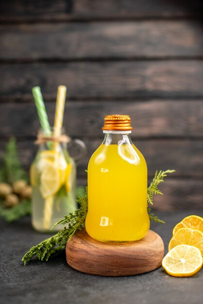 Vista frontal de la botella de jugo de naranja sobre tablero de madera y limonada