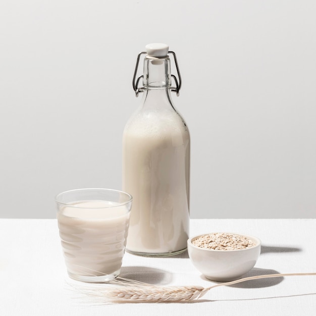 Vista frontal de la botella de leche con vidrio y avena