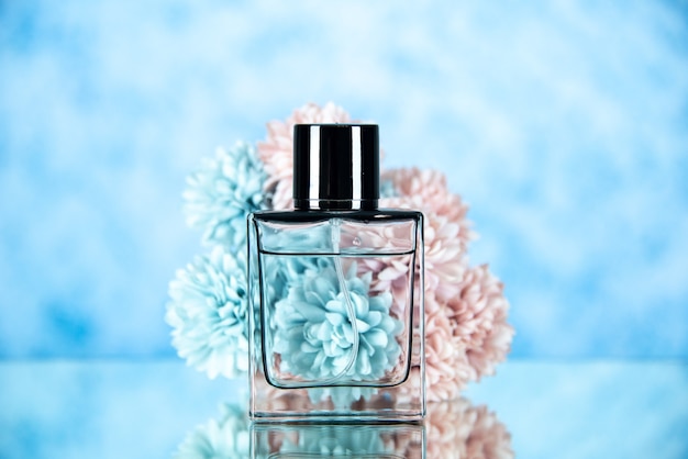 Vista frontal de la botella de perfume y flores en el espacio libre de fondo borroso azul claro