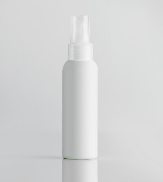 Vista frontal botella de plástico blanco con rociador en una pared blanca