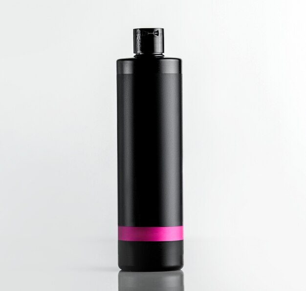 Vista frontal botella de plástico negro debajo del champú con una franja rosa