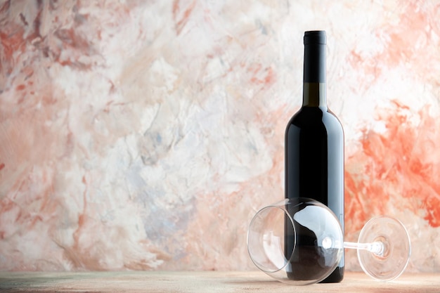 Vista frontal botella de vino con copa de vino sobre un fondo claro bebida alcohólica bar jugo limonada cena festiva foto uva
