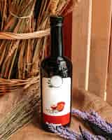 Foto gratuita una vista frontal botella de vino tinto negro junto con flores de color púrpura en la superficie de madera marrón