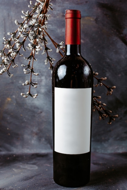 Vista frontal botella de vino tinto en la superficie gris